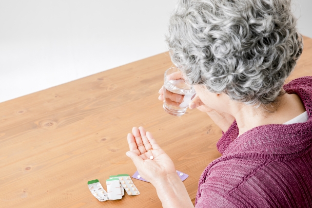 薬を飲む高齢女性